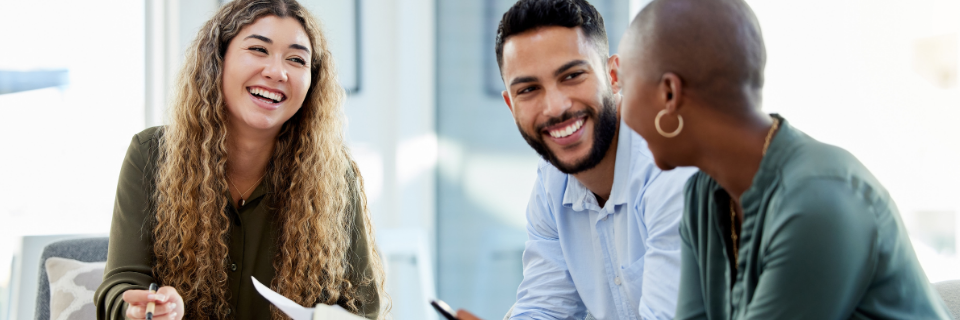 Team of workers sit around desk at office