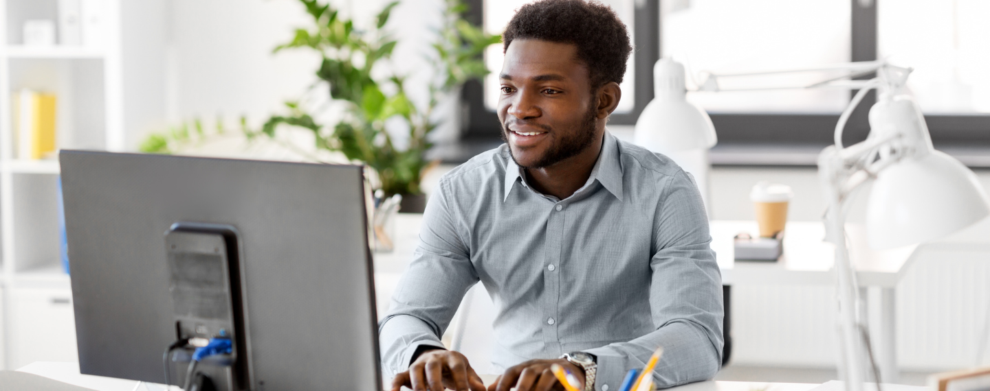 Man smiles sitting at desk looking at computer