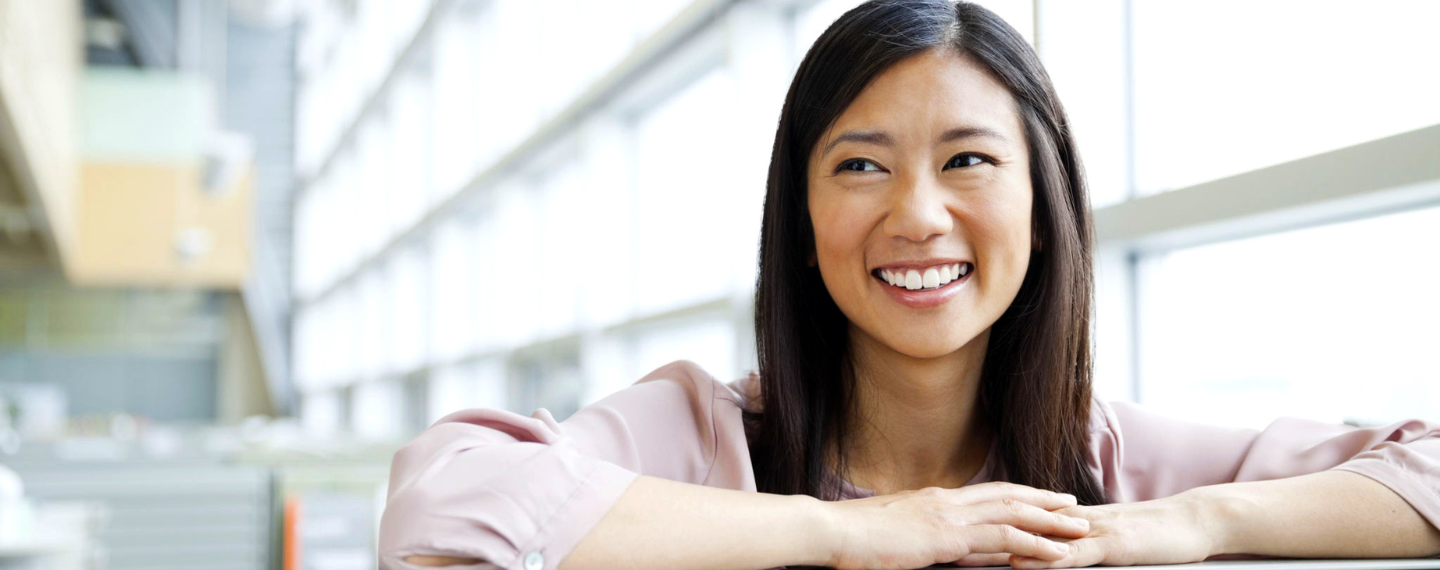 Woman smiles with hands on top of desk