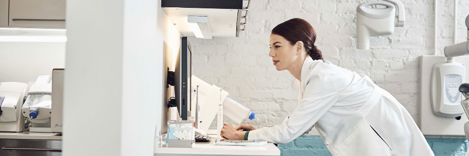 Provider in a white doctor suit leans over a desk