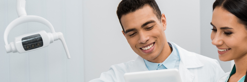 Two dentists smile near equipment