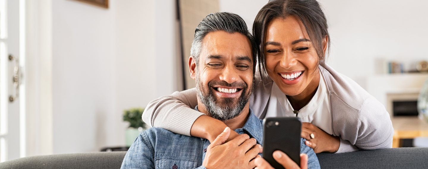 Man and woman smile looking at phone